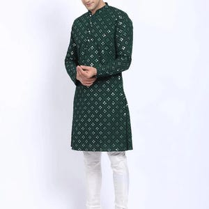 Puede incluir: Una kurta verde de manga larga con un patr&oacute;n geom&eacute;trico blanco y verde. La kurta tiene un cuello mandar&iacute;n y un cierre de bot&oacute;n. El modelo lleva pantalones blancos y zapatos marrones.