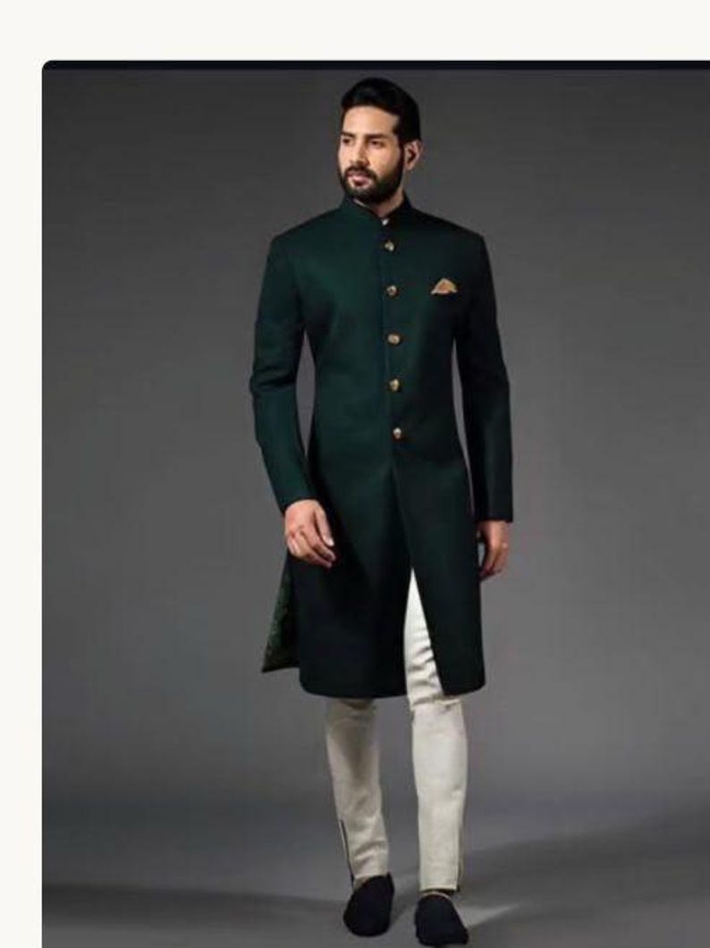 Peut inclure: Une veste sherwani vert fonc&eacute; arrivant au genou avec un col officier, des manches longues et une patte de boutonnage frontale orn&eacute;e de boutons dor&eacute;s. Une pochette dor&eacute;e est ins&eacute;r&eacute;e dans la poche poitrine gauche. Port&eacute;e avec un pantalon blanc cass&eacute;.