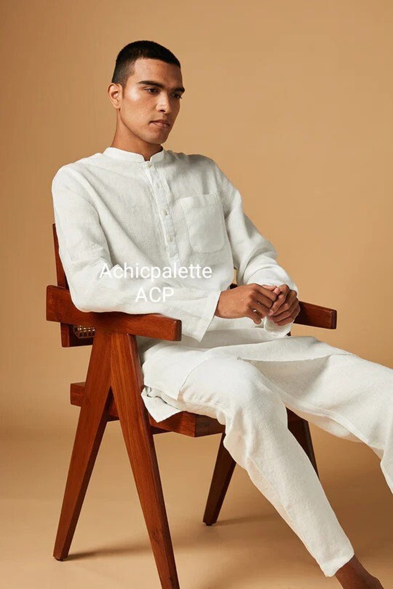 Puede incluir: Una persona con una camisa y pantalones de lino blanco se sienta en una silla de madera. La camisa tiene un cuello mandar&iacute;n y un cierre de botones en la parte delantera. El texto "Achicpalette ACP" es visible en la camisa.