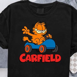 Gato divertido en coche PNG, dibujos animados de coches PNG, gato retro de dibujos animados, clipart de gato de carreras, arte de gato naranja genial, gato perezoso en coche, animal de dibujos animados conduciendo PNG
