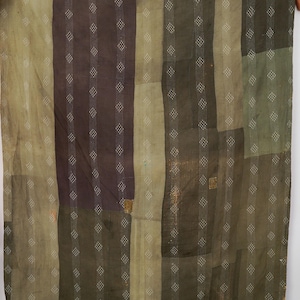 May include: A rectangular textile featuring a patchwork design of various fabric panels in shades of olive green, dark brown, and muted tan. The surface is covered in vertical rows of white stitched patterns and small diamond-shaped motifs.