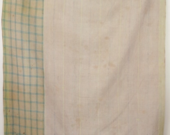 May include: A vintage quilt with a light brown background and a green and blue plaid border. The quilt is made of a thin, woven fabric and has a slightly worn appearance.