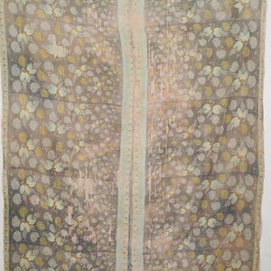 Puede incluir: Textil con estampado floral en tonos grises, amarillos y azules. El diseño presenta patrones florales y de puntos repetidos. Una franja vertical de verde pálido y rosa recorre el centro. El textil parece ligero y posiblemente vintage.