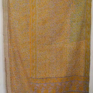 May include: A rectangular textile with a yellow and grey floral pattern. The fabric has vertical lines and a border with a floral design. The textile is likely a quilt or blanket, possibly handmade.