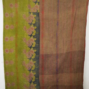 Puede incluir: Textil hecho a mano con un diseño floral. El lado izquierdo presenta un fondo verde con flores rosas, mientras que el lado derecho tiene un patrón de rayas marrones. El textil es probablemente un edredón o una manta, que muestra una mezcla de colores y texturas.