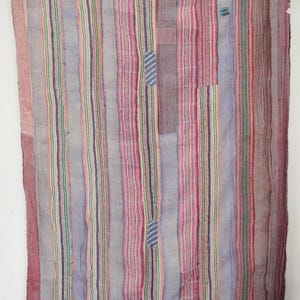May include: A vertically striped textile in shades of purple, pink, green, and blue. The fabric has a patchwork design with visible stitching and small patches of contrasting fabric. The overall aesthetic is vintage and handcrafted.
