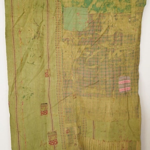 Op de afbeelding: Een vintage olijfgroen textiel met een patchwork ontwerp. De stof heeft verticale strepen, gestikte details en patches in verschillende tinten groen en rood. Het textiel heeft een versleten, verweerde uitstraling, wat duidt op leeftijd en gebruik.