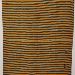Könnte beinhalten: Ein rechteckiges Textil mit einem sich wiederholenden Muster aus horizontalen senfgelben und dunkelblauen Streifen. Der Stoff weist durchgehend sichtbare feine Nähte auf und enthält drei kleine, unterschiedliche quadratische Flicken am rechten Rand.