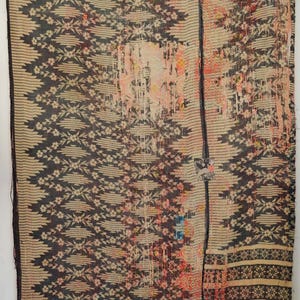 May include: A rectangular textile featuring a dark charcoal and cream floral pattern with vertical stripes and distressed sections in faded orange and pink. The fabric displays visible running stitch details throughout the surface.