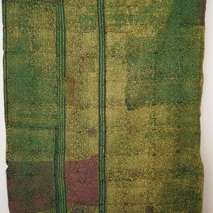 May include: A green and olive-toned textile with a floral pattern. The textile features vertical stripes and patches of darker green and maroon. The overall design is a patchwork of different patterns and colours.