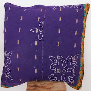 May include: Purple and gold embroidered throw pillow with a floral pattern. The pillow is made of a soft, quilted fabric and has a fringed edge.