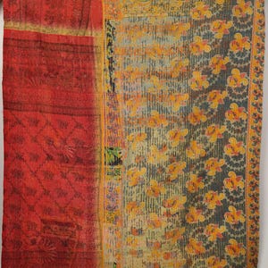 May include: A rectangular textile quilt featuring a patchwork design with a prominent vertical red section on the left side and a larger panel on the right displaying a dark grey background with repeating yellow floral patterns and visible stitching.