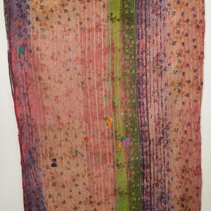 Puede incluir: Textil vintage con estampado floral en tonos rosa, morado, verde y beige. La tela presenta rayas verticales y un diseño de patchwork. El textil es probablemente un edredón o una manta, que muestra una estética bohemia.