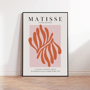 May include: A black and white poster with the text "MATISSE PAPIERS D&Eacute;COUP&Eacute;S" and a red abstract design on a pink background. The text at the bottom reads "70, RUE DE L'UNIVERSIT&Eacute;, PARIS-VII Du Vendredi 27 Fevrier au Samedi 28 Mars 1953."