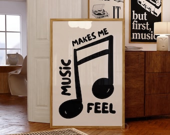 May include: A framed print with a large black musical note and the words "MUSIC MAKES ME FEEL" in a bold, handwritten style. Two other framed prints with music-related imagery are visible in the background. The room has a wooden floor and a wooden cabinet.