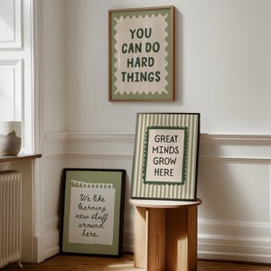 May include: Three framed wall art prints. The top print features the text "YOU CAN DO HARD THINGS" in dark green on a light green background with a scalloped border. The middle print displays "GREAT MINDS GROW HERE" in dark green on a striped background. The bottom print shows "We like learning new stuff around here." in dark green on a light green background.