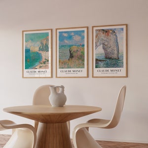 May include: Three framed art prints of seascapes by Claude Monet. The prints are in a light wood frame and feature the text "Claude Monet" and the title of the painting. The prints are hanging on a white wall.
