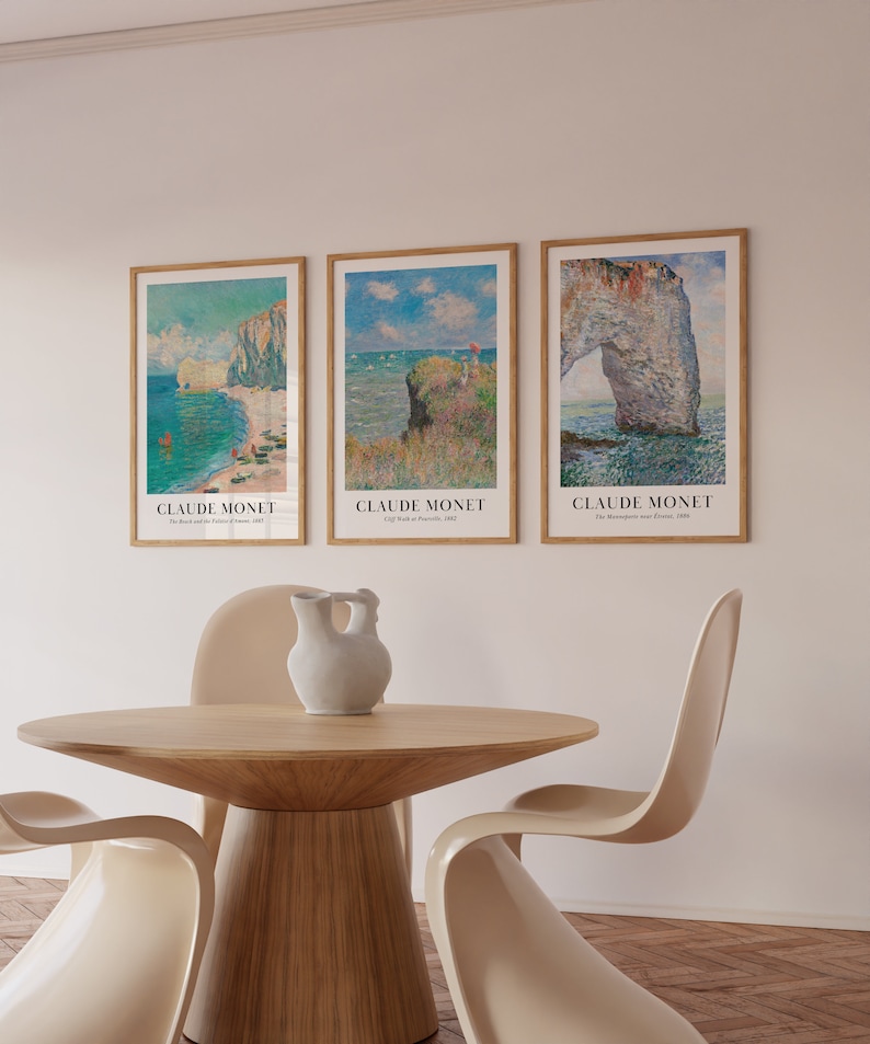 May include: Three framed art prints of seascapes by Claude Monet. The prints are in a light wood frame and feature the text "Claude Monet" and the title of the painting. The prints are hanging on a white wall.
