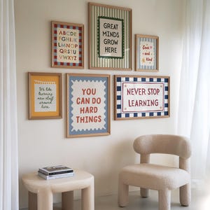 Puede incluir: Una pared de galería con seis láminas enmarcadas en madera clara. Las láminas incluyen un abecedario, un diseño de bloc de notas y cuatro pósteres con los textos: Great Minds Grow Here, Cool and Kind, You Can Do Hard Things y Never Stop Learning.