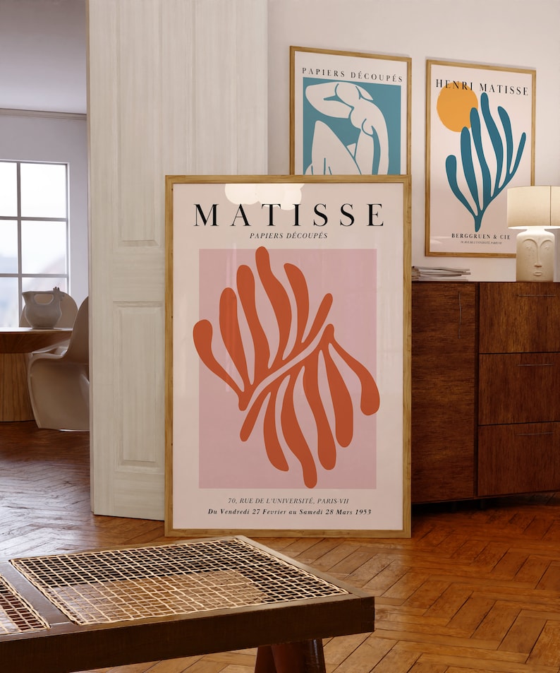 May include: A pink and orange poster with the text "MATISSE PAPIERS D&Eacute;COUP&Eacute;S" and a large orange abstract design. The poster also includes the text "70, RUE DE L'UNIVERSIT&Eacute;, PARIS VII Du Vendredi 27 Fevrier an Samedi 28 Mars 1953".