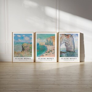 May include: Three framed art prints of seascapes by Claude Monet. The first print shows a cliff with a red umbrella, the second shows a beach with a rocky cliff, and the third shows a large rock archway.