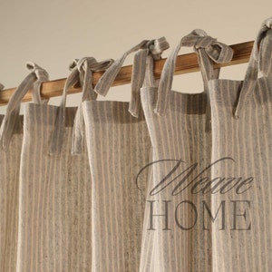 May include: Set of five beige and white striped linen curtains with fabric ties. The curtains are hung on a wooden rod and feature the text "Weave Home".