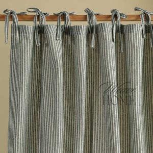 May include: A pair of blue and white striped curtains with a simple tie-top design. The curtains are made of a lightweight fabric and have a relaxed, casual look.
