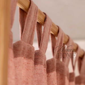Könnte beinhalten: Nahaufnahme eines Satzes rosa Leinenvorhänge mit einer Holzgardinenstange. Die Vorhänge sind mit Stoffschlaufen zurück gebunden.
