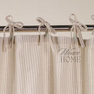 May include: A pair of white and blue striped curtains with a simple tie-top design. The curtains are hung on a silver rod.
