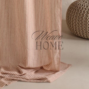 May include: A close-up of a red and white striped fabric curtain with the text "More Home" printed on it. The curtain is folded and draped over a light brown surface.