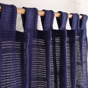 May include: A set of navy blue crocheted curtains with a woven pattern. The curtains are hung on a wooden rod.