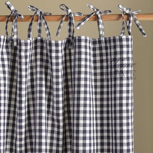 May include: A set of four blue and white gingham check curtains with ties at the top. The curtains are hung on a wooden rod.