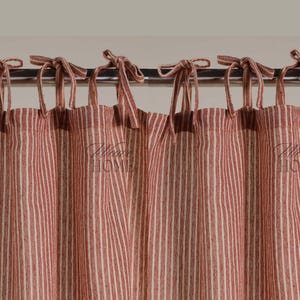 Puede incluir: Cortinas de rayas rojas y blancas con un diseño de lazo en la parte superior. Las cortinas están hechas de una tela ligera y tienen un estilo informal de granja.