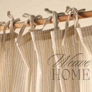 May include: A set of beige and white striped curtains with a woven texture, hanging from a wooden rod. The curtains have a simple, rustic look and are tied back with fabric loops.