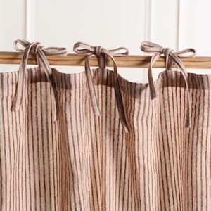 May include: A pair of brown and white striped curtains with a simple tie-top design. The curtains are made of a lightweight fabric and have a relaxed, casual look.