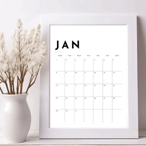 Peut inclure: Un calendrier blanc encadré avec le mois de janvier imprimé en noir. Le calendrier est vide et les jours de la semaine sont listés en haut.
