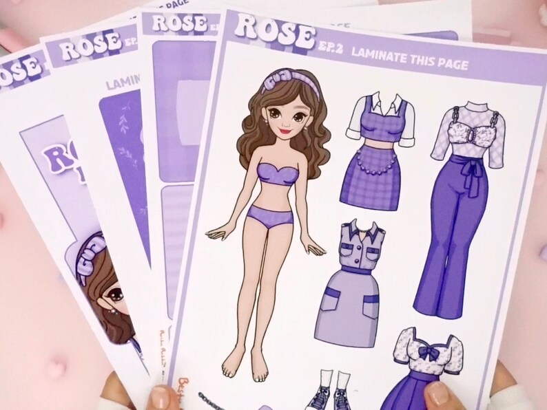 May include: A paper doll set featuring a girl with brown hair and purple outfits. The set includes a variety of clothing options, including a dress, a skirt, and a top. The paper doll set is printed on white paper with a purple background. The text "ROSE EP.2 LAMINATE THIS PAGE" is printed on the page.