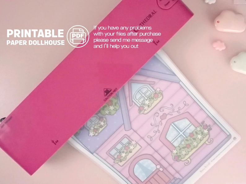 Op de afbeelding: Een printbaar papieren poppenhuisontwerp met een roze omslag en de tekst "PRINTABLE PAPER DOLLHOUSE". De illustratie van het poppenhuis toont een roze huis met bloembakken en een hartvormig wijnstokontwerp. De tekst "If you have any problems..." is ook zichtbaar.