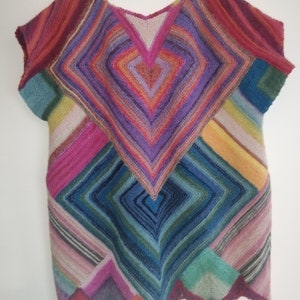 Könnte beinhalten: Ein farbenfrohes gehäkeltes Oberteil mit einem geometrischen Muster aus Quadraten und Dreiecken. Das Oberteil hat kurze Ärmel und einen V-Ausschnitt.