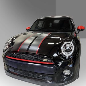 以下が含まれることがあります： 黒いミニクーパー車。シルバーと黒のレーシングストライプと赤いアクセントが特徴。赤いサイドミラーとフロントグリルにはユニオンジャックのエンブレム。ヘッドライトは丸型です。