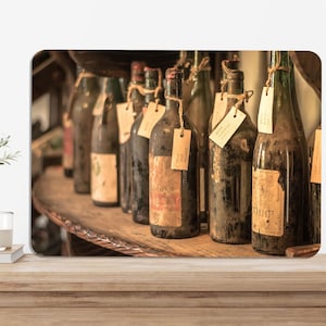 以下が含まれることがあります： 木製の棚に並んだ、ラベルとコルクが付いたヴィンテージワインボトルのコレクション。ボトルは様々な色で、経年劣化の兆候が見られるものもある。各ボトルにはタグが付いています。
