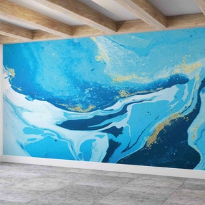 Op de afbeelding: Een blauwe en witte abstracte muurmuur met gouden accenten. De muurschildering heeft draaiende patronen en texturen die doen denken aan water.