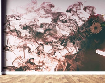May include: A woman's face is partially obscured by wispy smoke, which appears to be flowing from her head. She is wearing a floral crown and looking to the side. The background is a light pink.