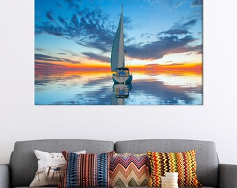 Könnte beinhalten: Leinwanddruck eines Segelboots auf ruhigem Wasser bei Sonnenuntergang. Der Himmel wechselt von Blau zu Orange und Rot und spiegelt sich im Wasser. Das Segelboot hat ein weißes Segel und einen blauen Rumpf.
