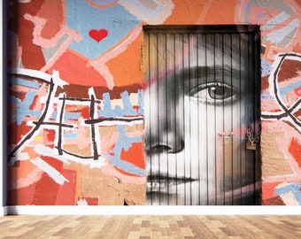 May include: A colourful graffiti wall with a black and white portrait of a person's face painted on a door. The portrait is partially obscured by the door's vertical slats. The graffiti includes a red heart, black lines, and various shades of pink, blue, and orange.