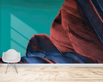 May include: A teal wall with a large abstract design of red and blue feathers. A white chair sits in front of the wall.