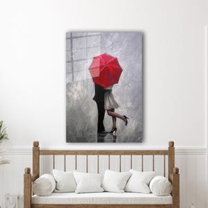 May include: A painting depicting a couple standing under a red umbrella in the rain. The man is wearing a black suit and the woman is wearing a white dress. They are both smiling and looking at each other.