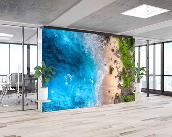 May include: An aerial view of a beach with turquoise water crashing on the shore. The beach is sandy with rocks and green vegetation. The image is a wall mural.