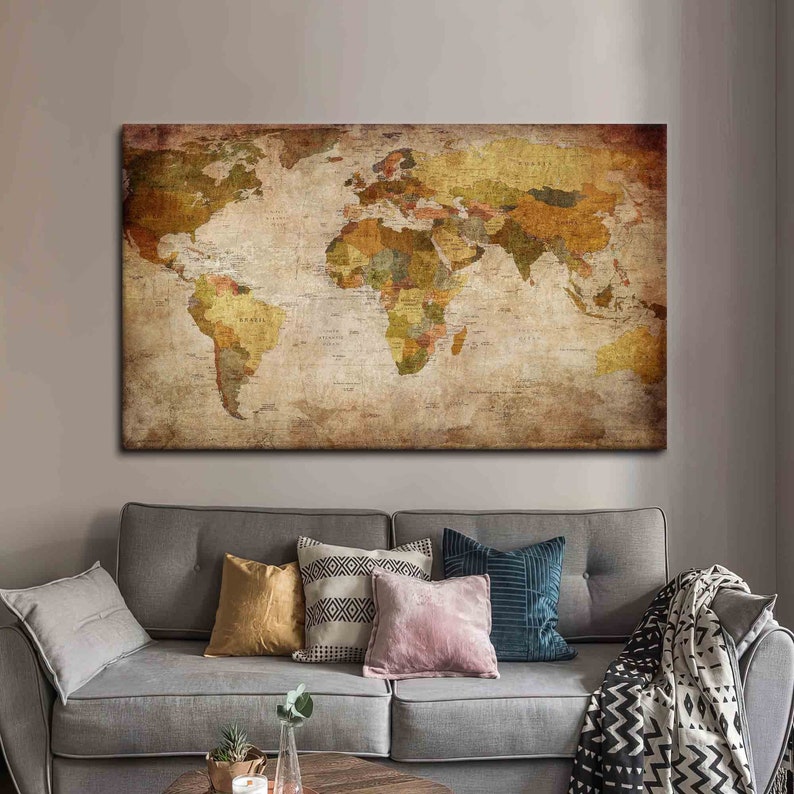 May include: A vintage-style world map canvas print with a distressed, aged look. The map is in shades of brown, green, and yellow, with country borders and names visible. The print is displayed on a wall above a gray couch with pillows and a throw blanket.