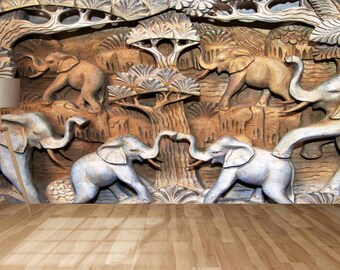 May include: A wooden wall carving depicting a scene of elephants in a jungle setting. The elephants are carved in a realistic style and are shown in various poses. The carving is painted in shades of brown and gray.